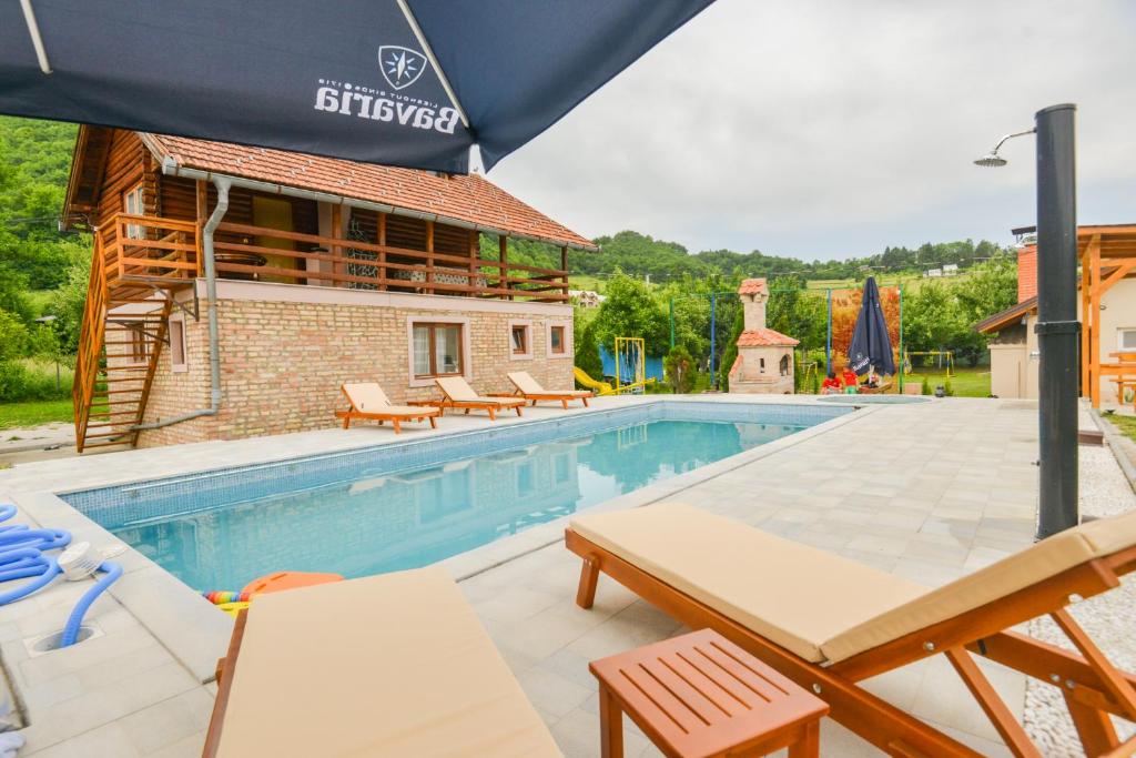 einen Pool mit Tischen und Stühlen neben einem Gebäude in der Unterkunft Villa Miris Prirode Zenik in Ilidža