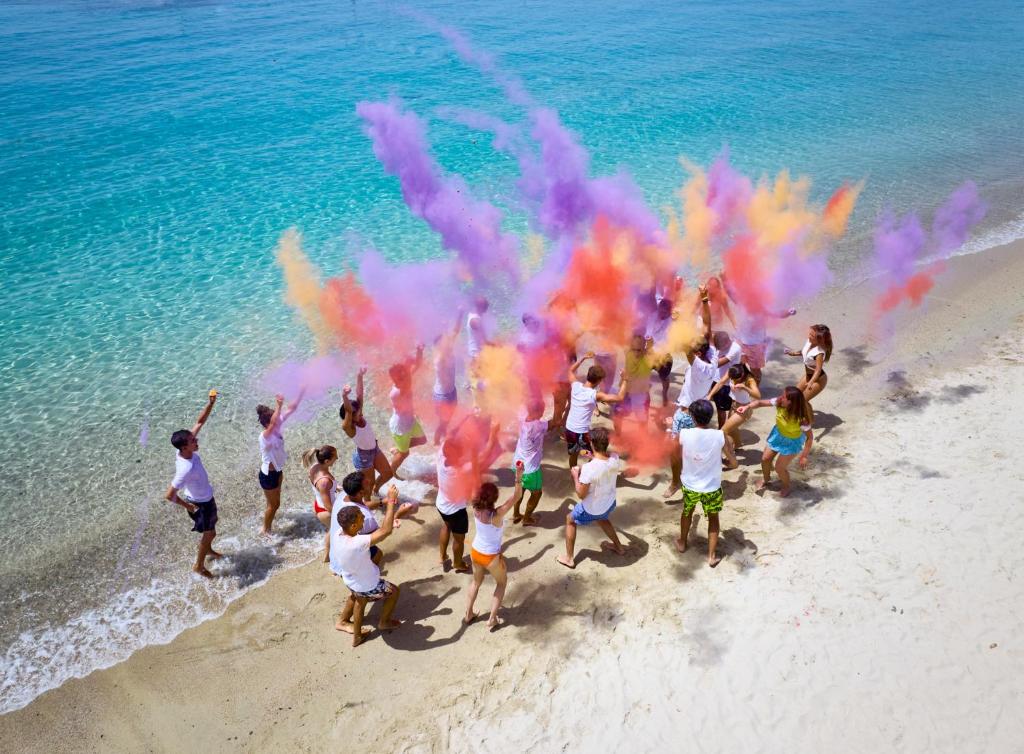 a group of children playing on the beach with colored smoke at Calaserena Resort in Geremèas