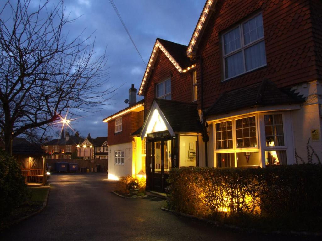 a house with lights on a street at night at Corner House Hotel Gatwick with Holiday Parking in Horley