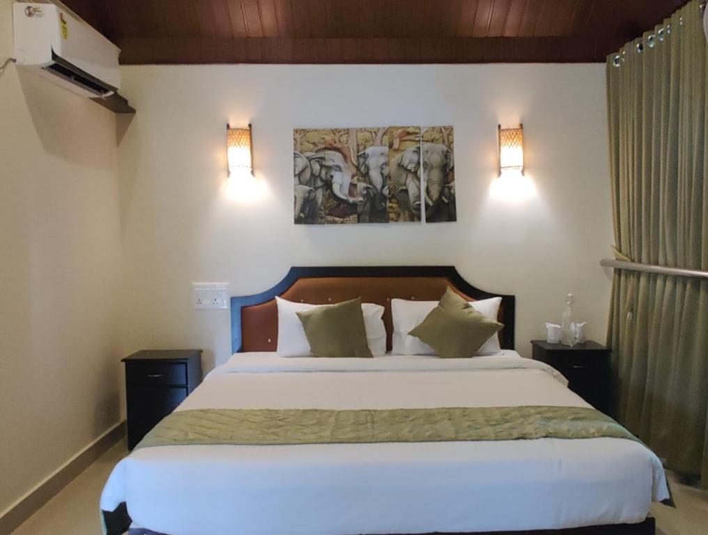 a bedroom with a large white bed with two lights at Wayanad Kuruva Isles Jungle Resort in Chekadi
