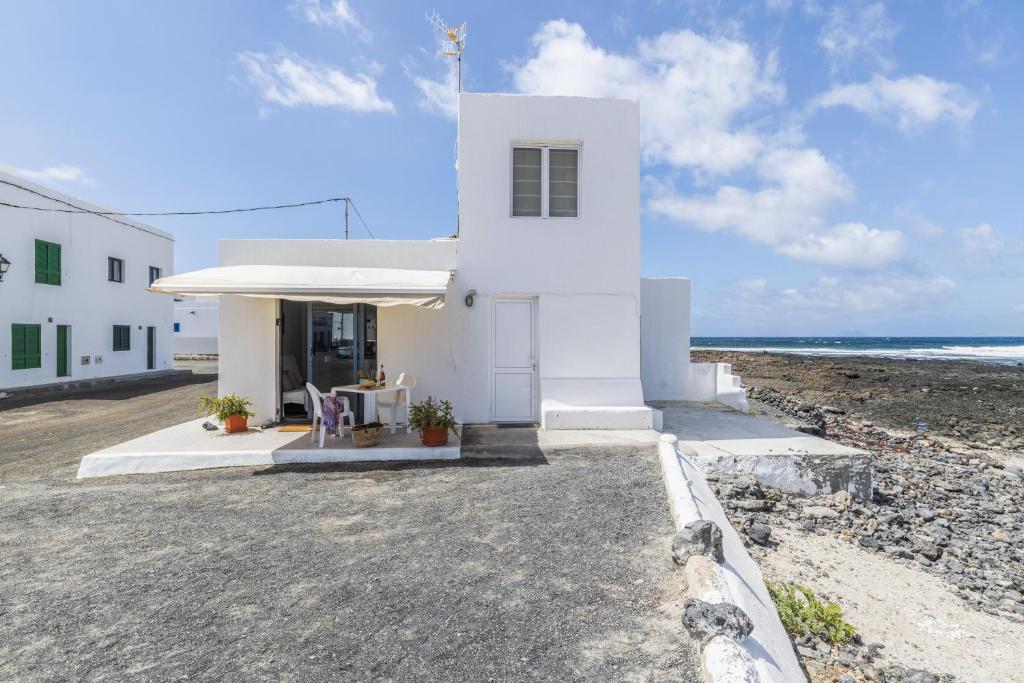 a white building on the beach next to the ocean at La Casita Del Mar in Caleta de Caballo