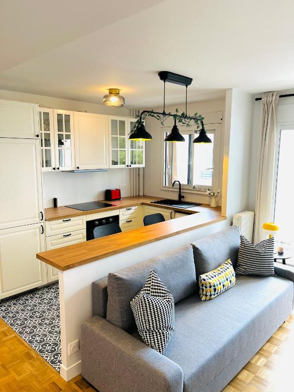 un salon avec un canapé et une cuisine dans l'établissement Défense-2rooms-ForWork-balcony-freeparking, à Courbevoie