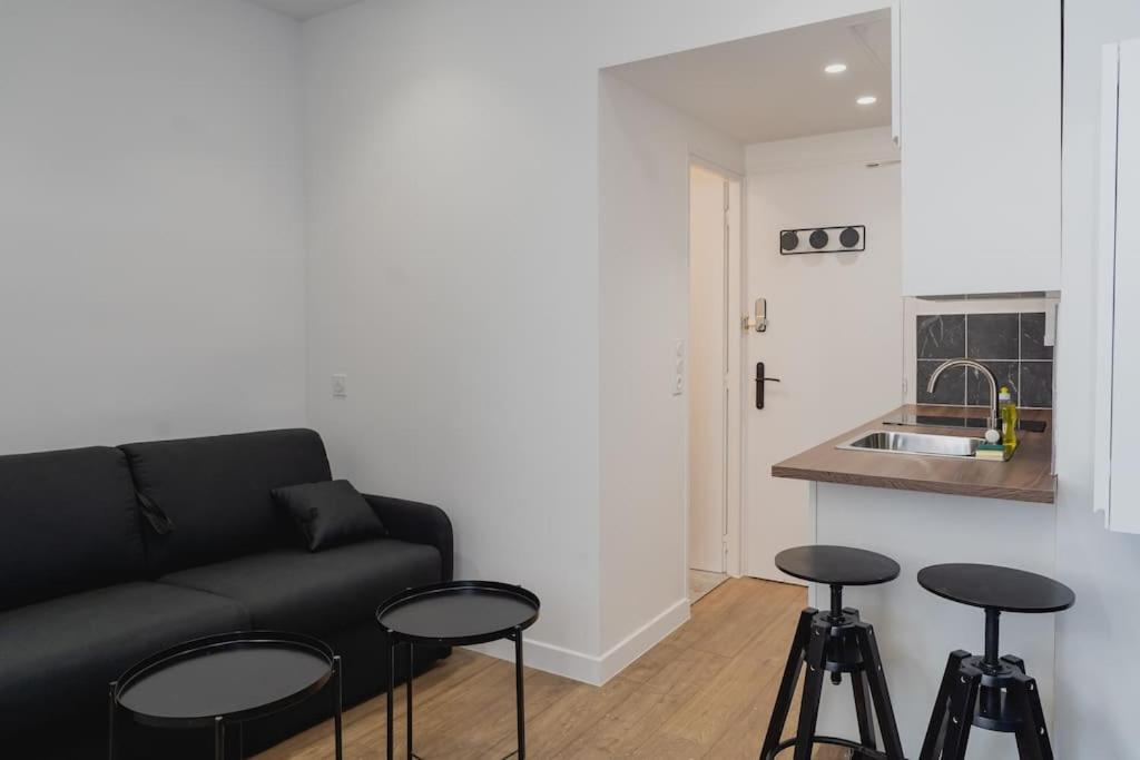 - un salon avec un canapé noir et des tabourets dans l'établissement Studio L'épine, à Chambéry