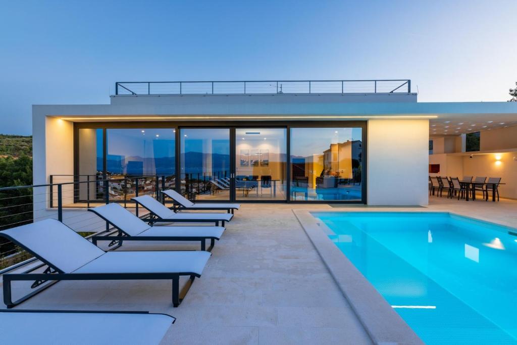 a row of lounge chairs next to a swimming pool at Beautifull Villa Adriatis with pool in Brač in Sutivan