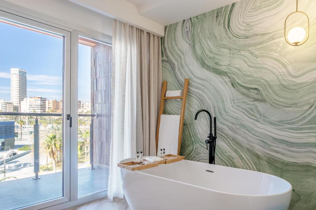 a bathroom with a tub and a large window at INNSiDE by Meliá Alicante Porta Maris in Alicante
