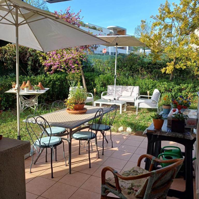 un patio avec une table, des chaises et un parasol dans l'établissement The Flower- Townhouse with air conditioning and garden!, à Montpellier