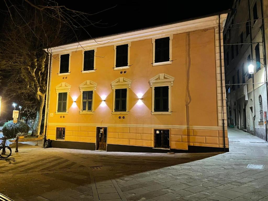 un bâtiment jaune avec des fenêtres donnant sur une rue la nuit dans l'établissement Levanto Rentals, à Levanto