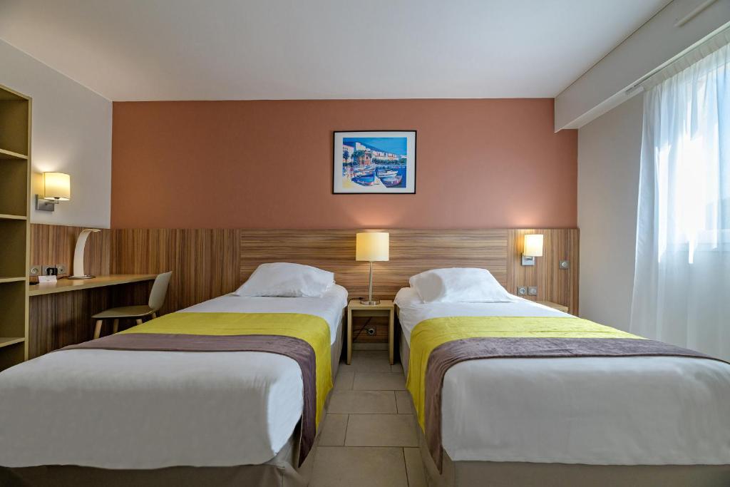 a hotel room with two beds and a window at Best Western Plus Ajaccio Amirauté in Ajaccio