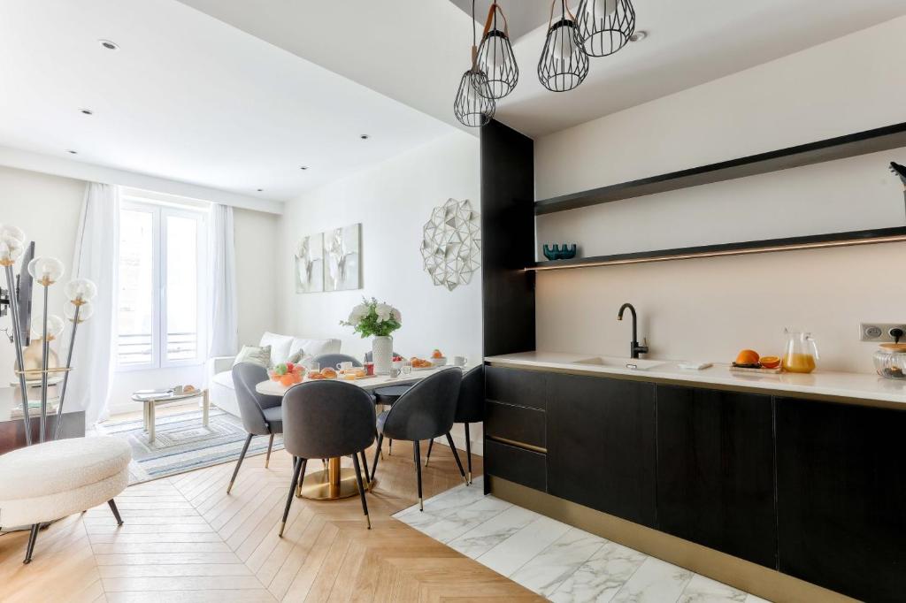 une cuisine avec des armoires noires, une table et des chaises dans l'établissement Family Retreat - Le Marais - with AC, à Paris