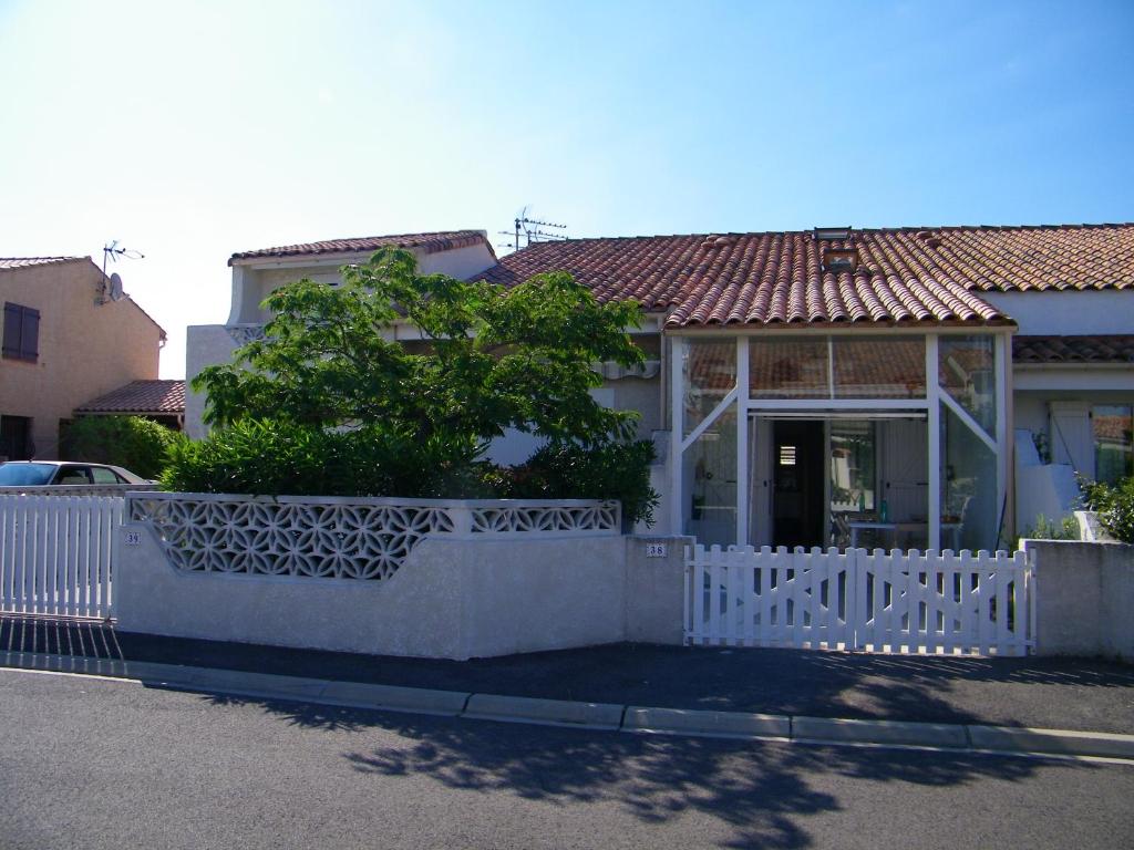 une clôture blanche devant une maison dans l'établissement maison pour vacance a la mer, à Port-la-Nouvelle
