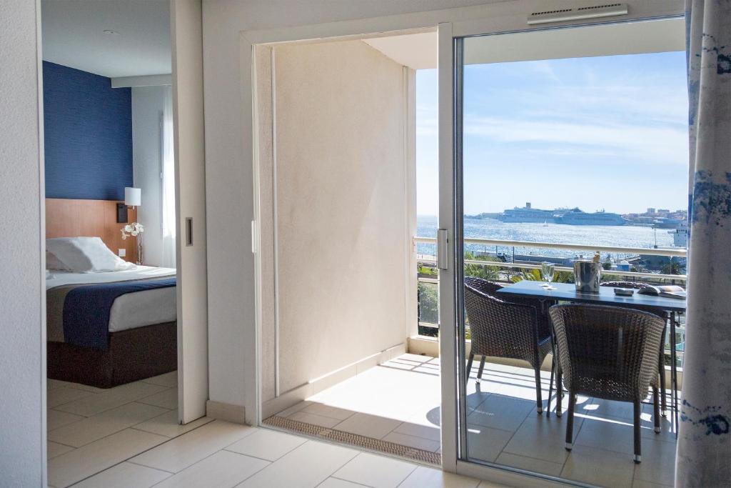 a room with a balcony with a bed and a view of the ocean at Best Western Plus Ajaccio Amirauté in Ajaccio