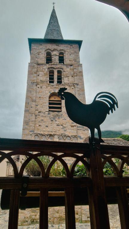 a statue of a rooster on a fence in front of a tower at Ço desde Viandol in Bossost