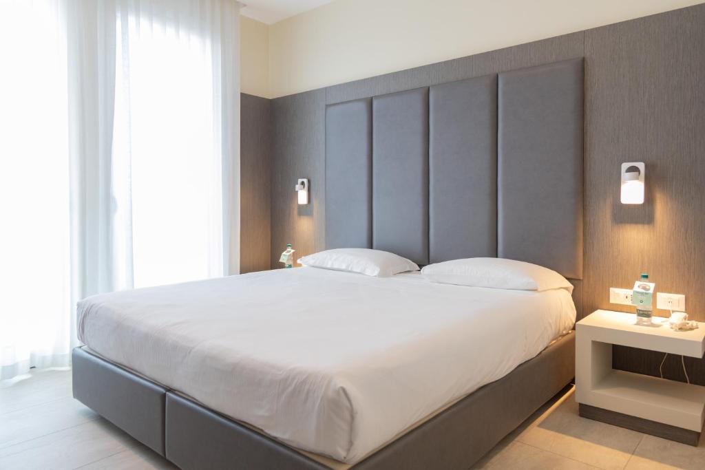 a bedroom with a large bed with white sheets at Mosella Suite Hotel in Sottomarina