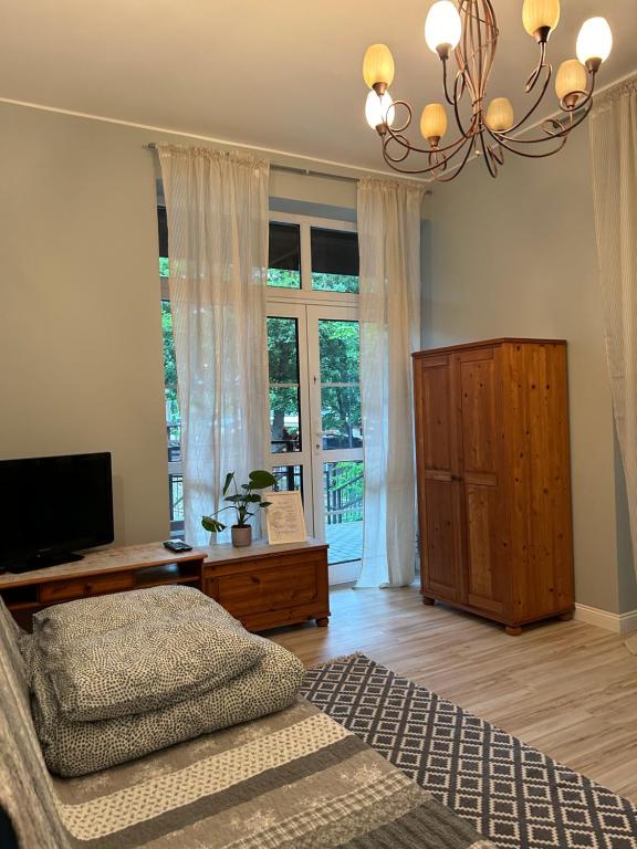 Schlafzimmer mit einem Bett, einem TV und einem Kronleuchter in der Unterkunft Apartament Pastelowy in Krynica Morska