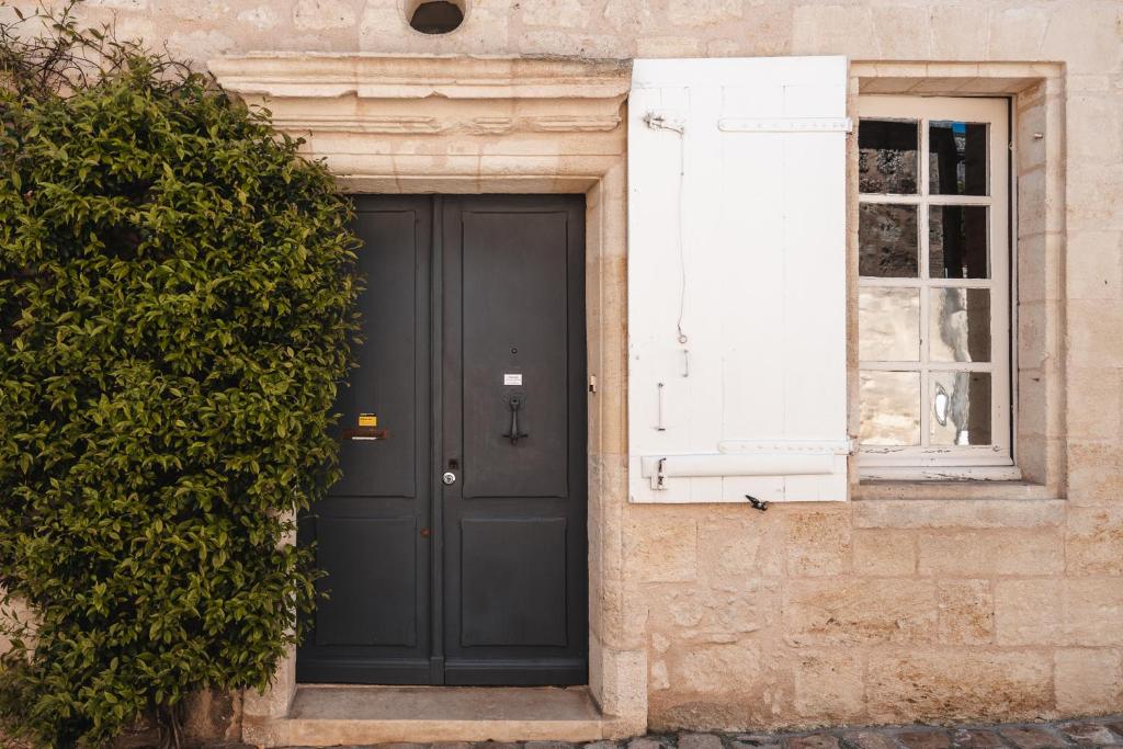 une porte noire sur un bâtiment avec une fenêtre dans l'établissement logis-des-cordeliers, à Saint-Émilion