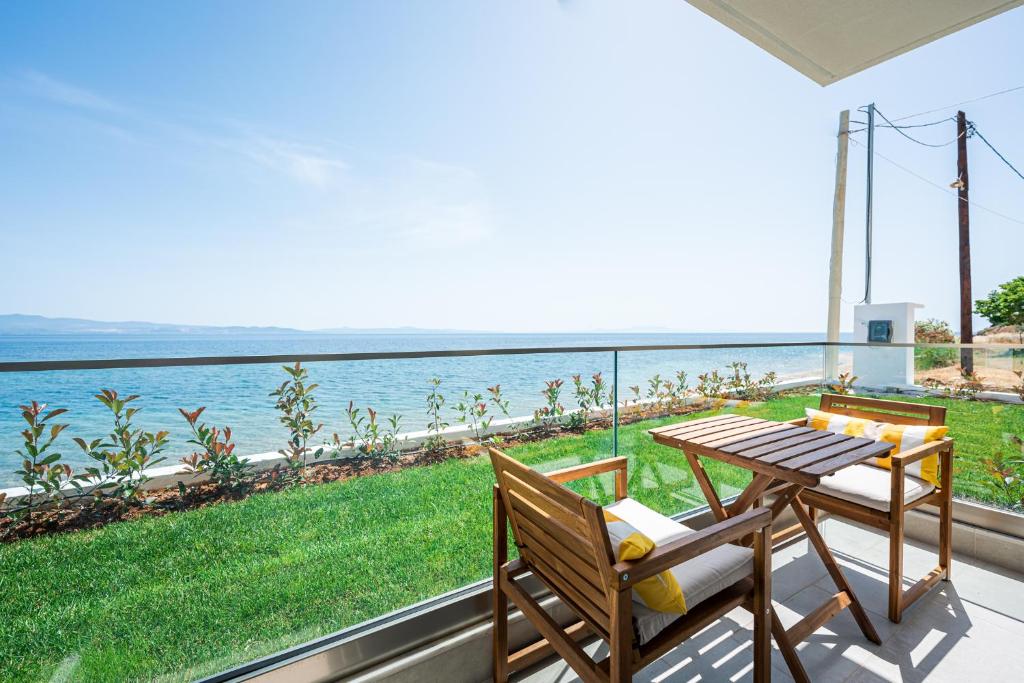 a balcony with a table and chairs and a view of the ocean at Azzurro e Verde by RentalsPro - Nea Potidaia Halkidiki in Nea Potidaea
