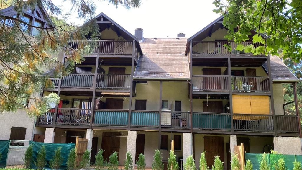 un immeuble d'appartements avec balcon et arbres dans l'établissement Le Coquelicot de Luchon, à Luchon