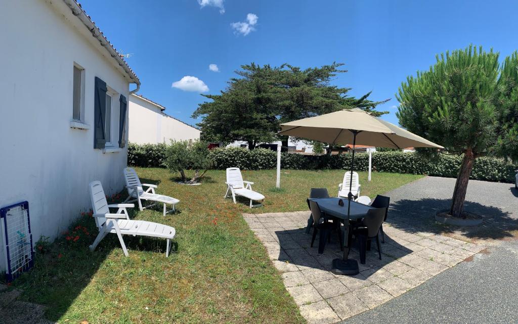 un patio avec une table, des chaises et un parasol dans l'établissement La Berardiere du centre, à Saint-Hilaire-de-Riez