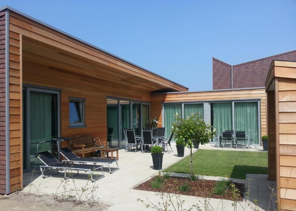 een huis met een patio met stoelen en tafels bij BONNIES Beach & Spa DuinNest in Cadzand-Bad