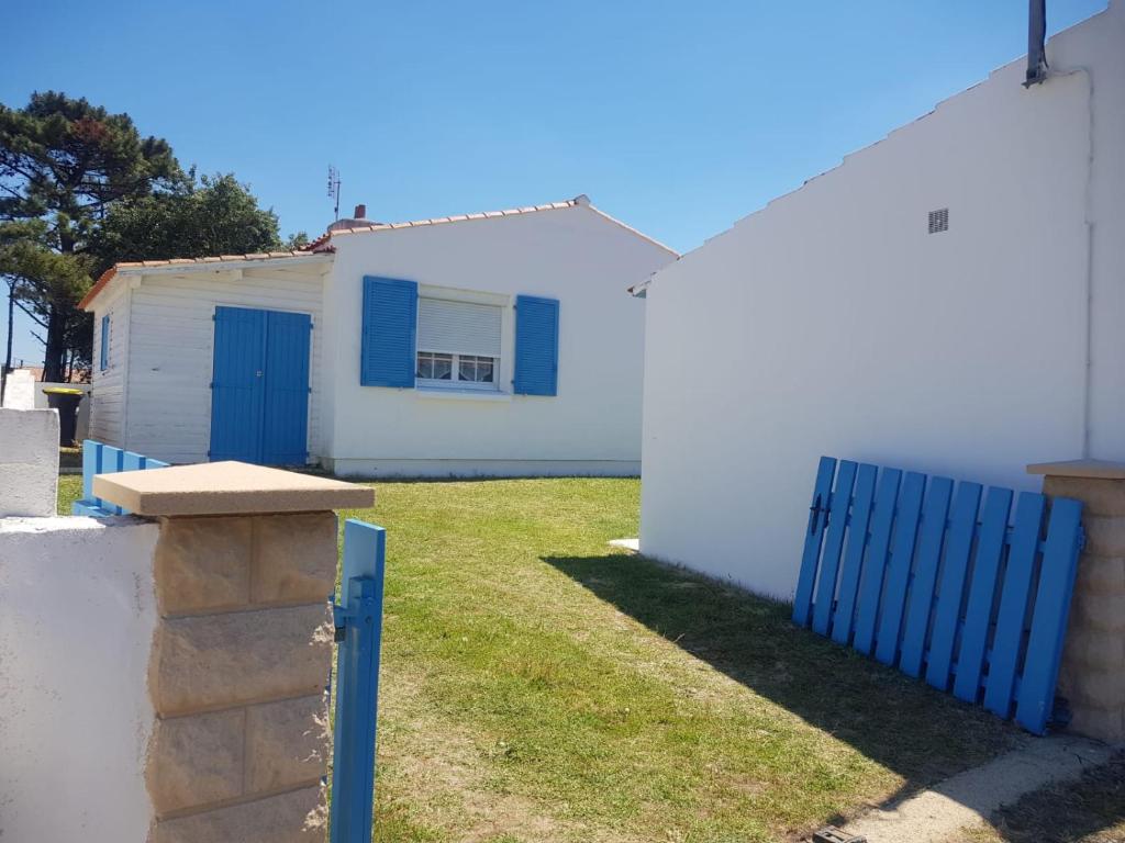 une maison blanche avec des portes bleues et une clôture dans l'établissement Maison Madoret 6 personnes, à Saint-Hilaire-de-Riez