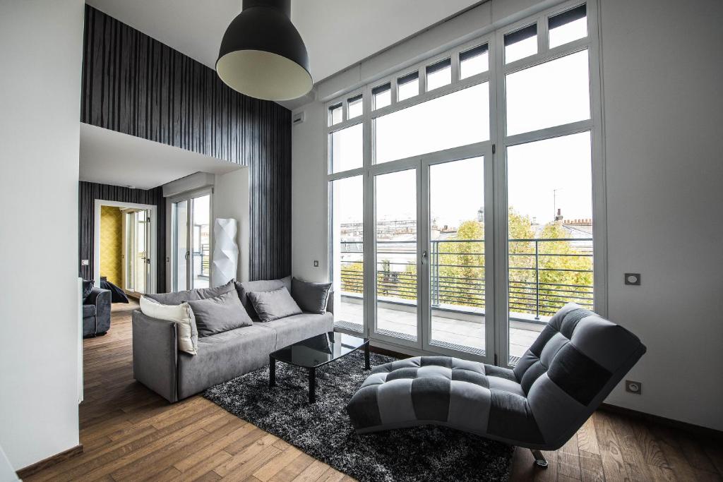 a living room with a couch and a large window at Les Appartements Paris Clichy in Clichy