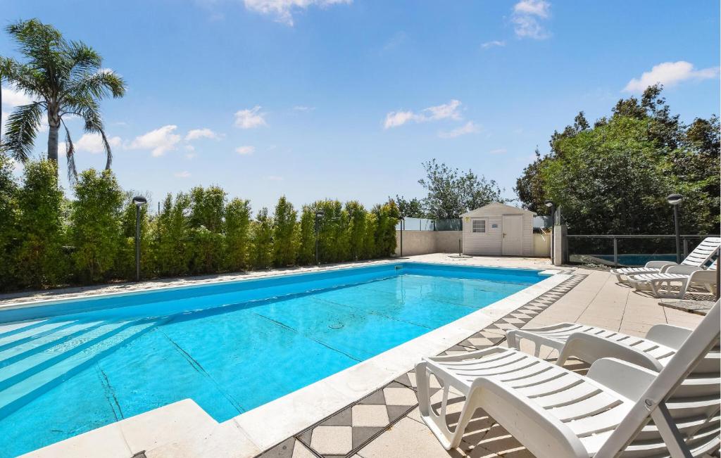 a swimming pool with two lawn chairs and a swimming pool at Pet Friendly Apartment In Monterosso in Fleri