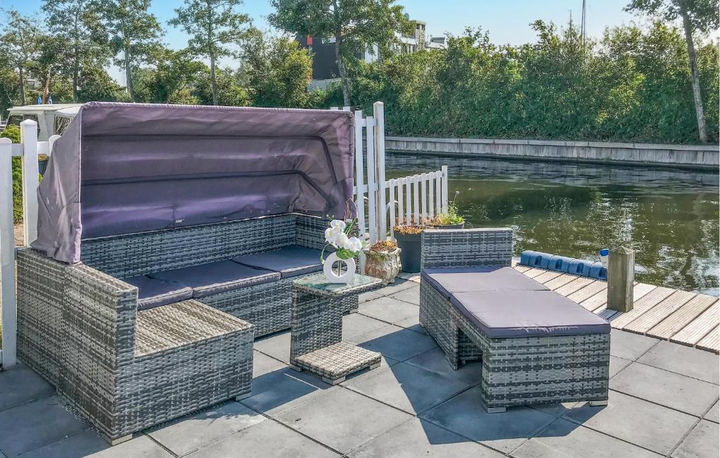 a patio with wicker chairs and a cover next to the water at 3 Bedroom Gorgeous Home In Lemmer in Lemmer