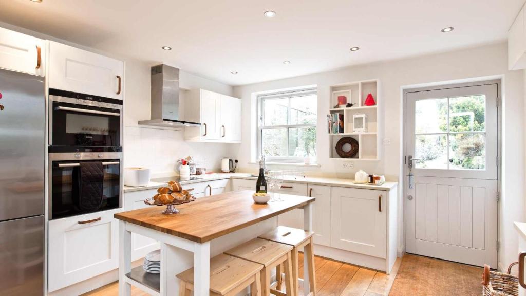 a kitchen with white cabinets and a wooden table at Edge Cottage in Curbar