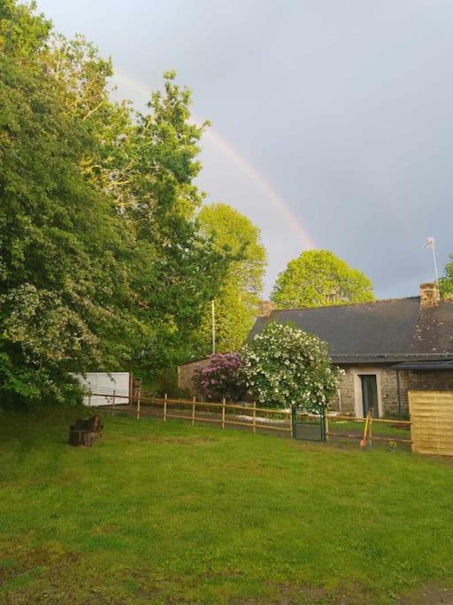 un arc-en-ciel au-dessus d'une cour avec une clôture et une maison dans l'établissement Notre essentiel gîte en Bretagne, à Ploërdut