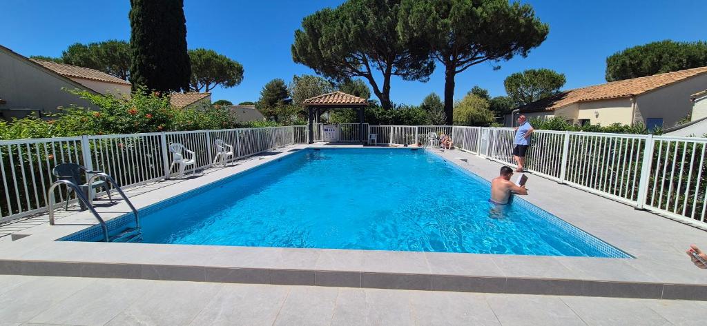un homme et un garçon debout dans une piscine dans l'établissement Villa 40m2 cosy avec piscine, clim, parking privé, à La Grande Motte