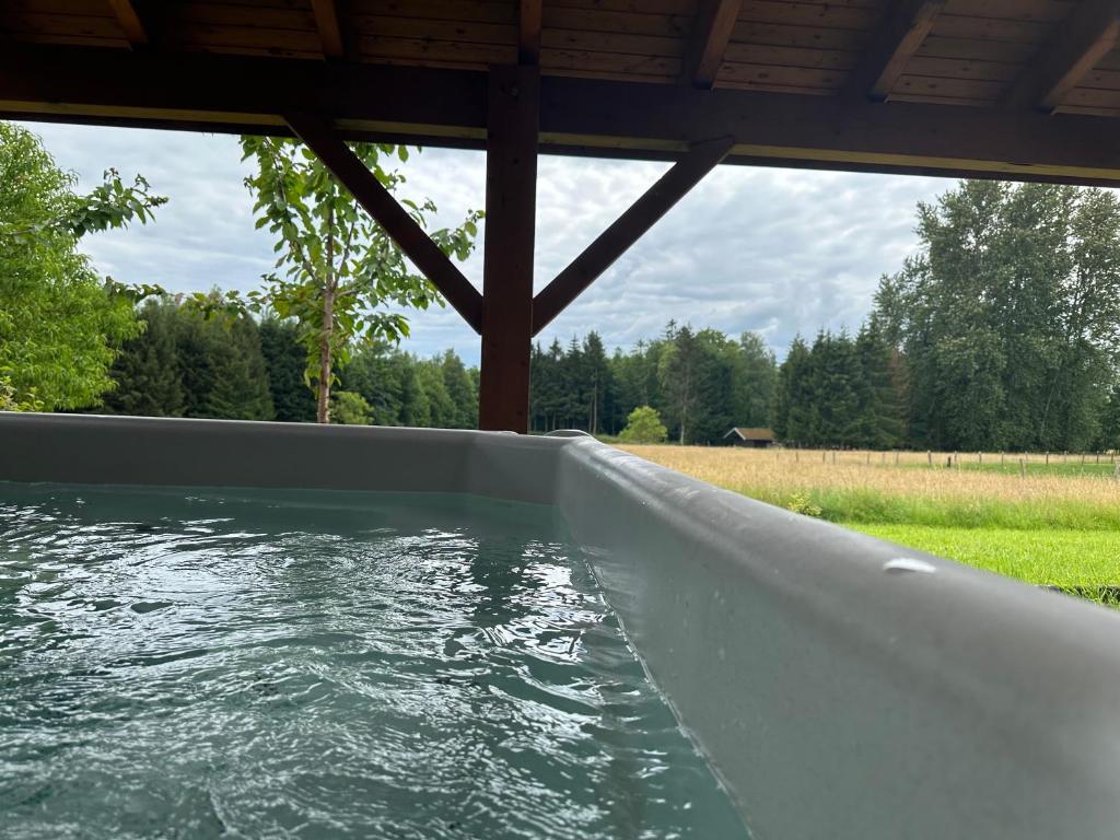 une baignoire remplie d'eau à côté d'un champ dans l'établissement Chalet dans un écrin de verdure avec SPA privatif, à Jeanménil