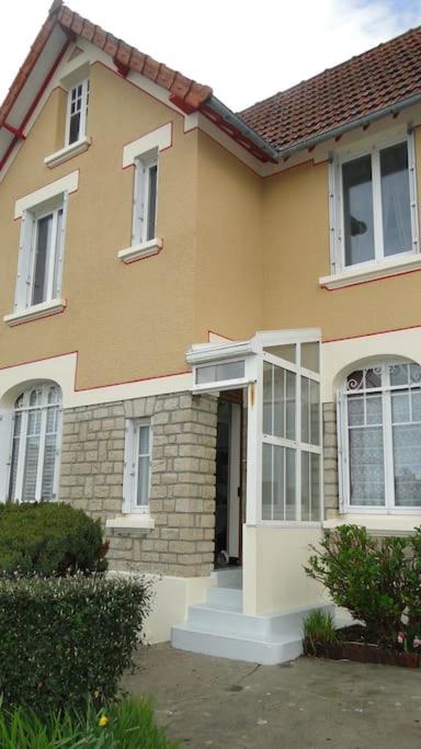 une maison jaune avec une porte et une véranda dans l'établissement gite de mer familial, plage et commerces à pied, à Grandcamp-Maisy