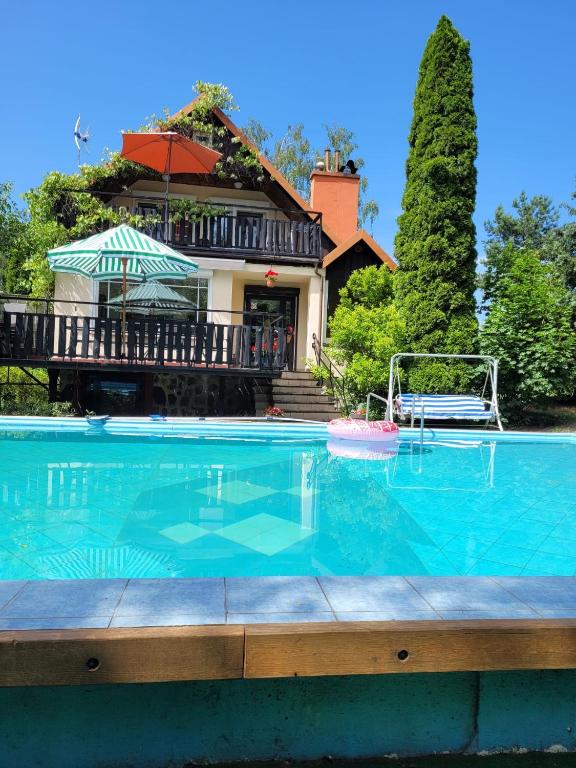a large swimming pool in front of a house at Holiday Villa Żuromino in Żuromino