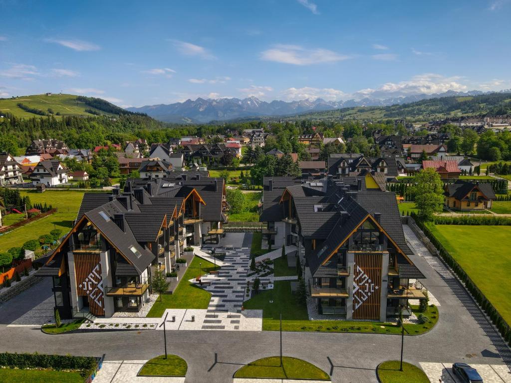 Aerial view of contemporary chalet-style resort buildings surrounded by greenery and distant mountain range