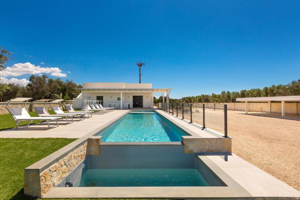 a swimming pool with chairs and a house at Sinfonia delle Onde by Perle di Puglia in San Pietro in Bevagna