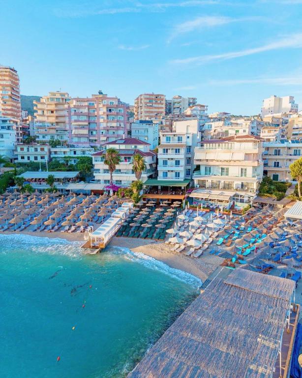 a beach with chairs and umbrellas and the ocean at Vila e Bardhe Butique Hotel in Sarandë
