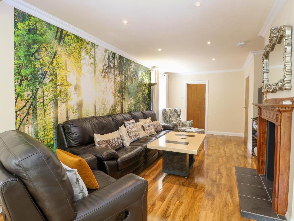 un soggiorno con un divano in pelle e un tavolo di Cedar Cottage a Norwich