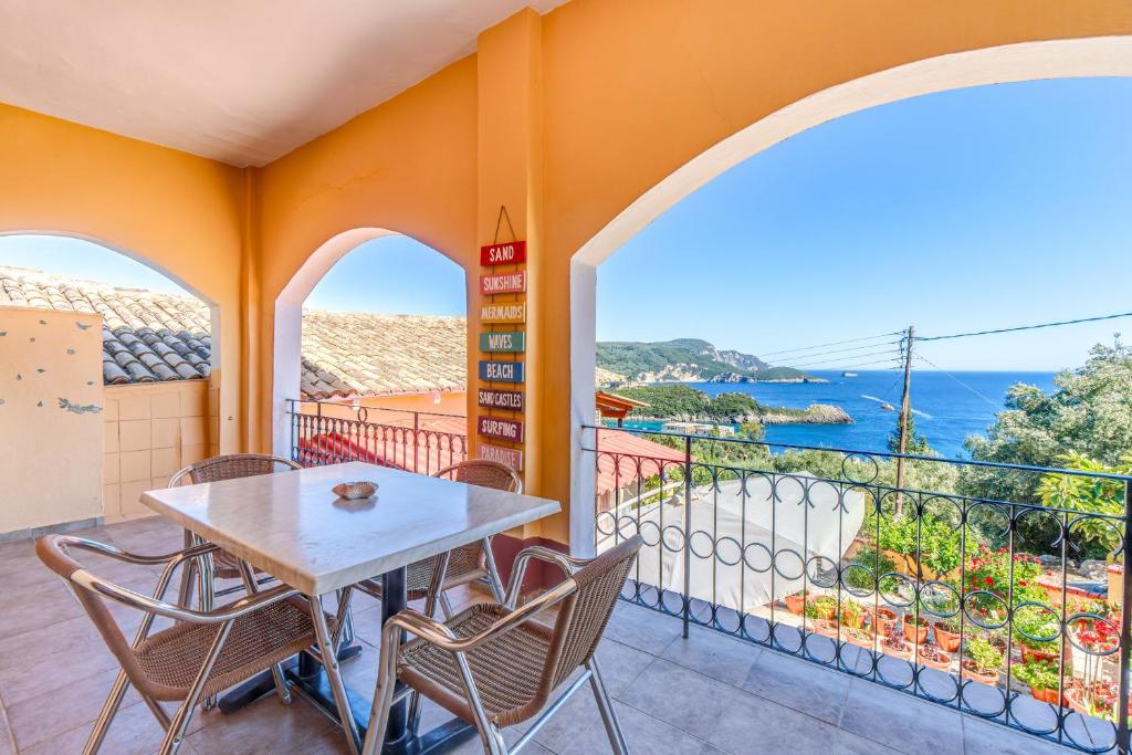 a table and chairs on a balcony with a view of the ocean at Two bedrooms apartment Vasillis in Paleokastritsa