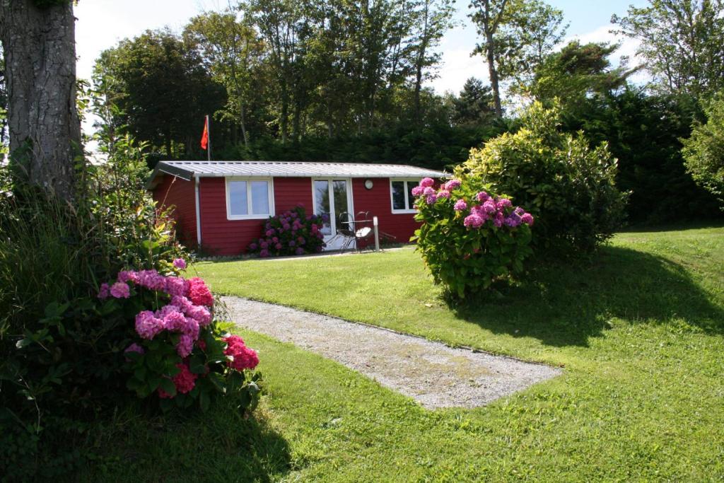 une petite maison rouge avec des fleurs devant elle dans l'établissement Le Randodo, à Quiberville