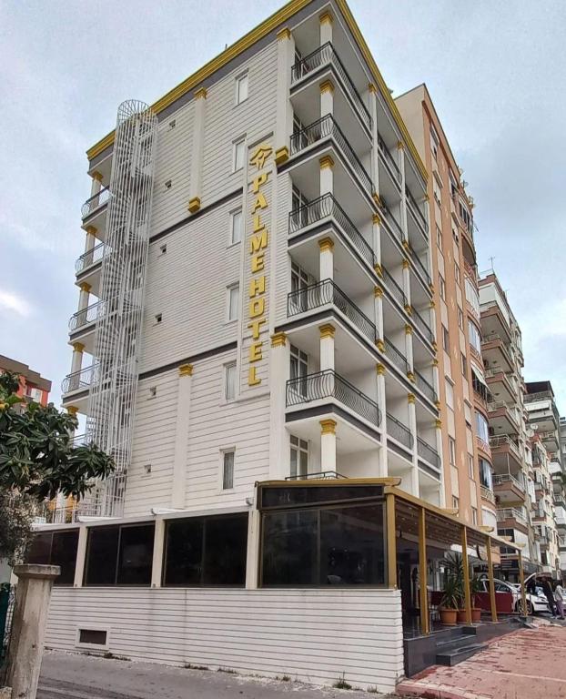 a tall white building with a yellow sign on it at Bayındır Palme Hotel in Antalya
