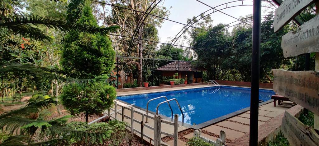 a swimming pool in the middle of a garden at Wayanad Kuruva Isles Jungle Resort in Chekadi