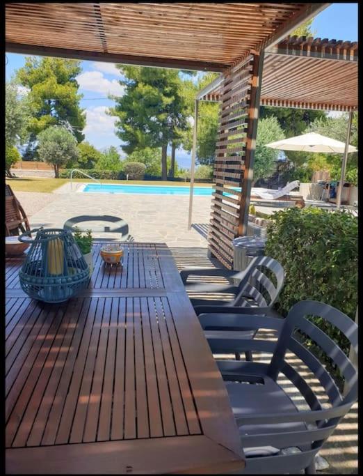 a wooden deck with a table and chairs and a pool at Villa Terrina in Áyioi Apóstoloi