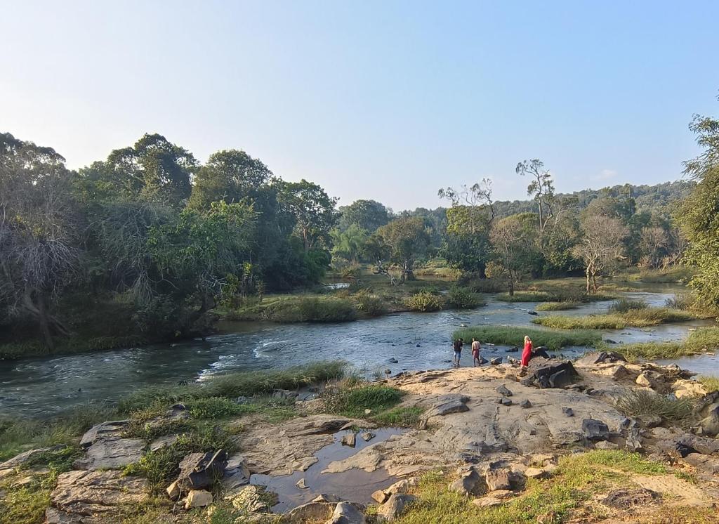 a group of people standing on a rock near a river at Wayanad Kuruva Isles Jungle Resort in Chekadi
