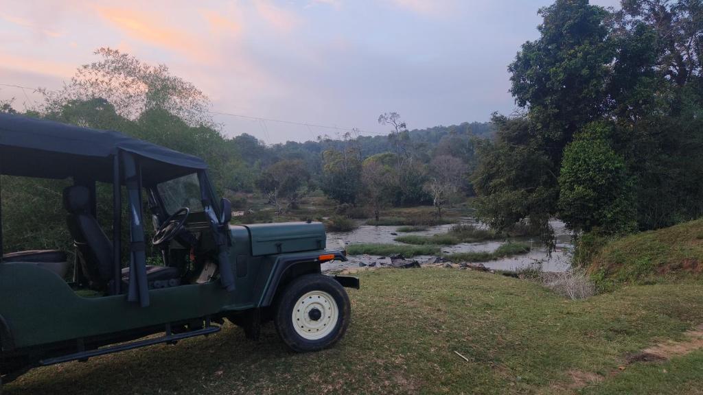 a green jeep parked in a field next to a river at Wayanad Kuruva Isles Jungle Resort in Chekadi