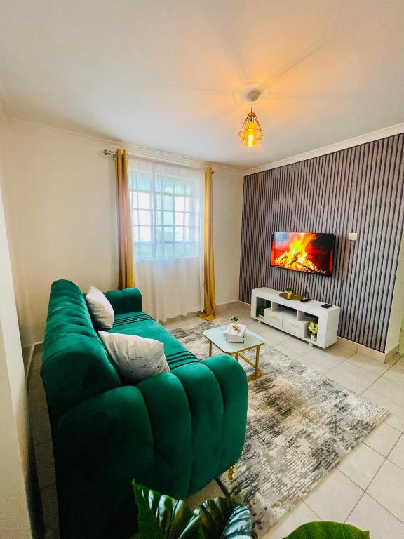a living room with a green couch and a tv at Bella Homes Thika Town in Thika