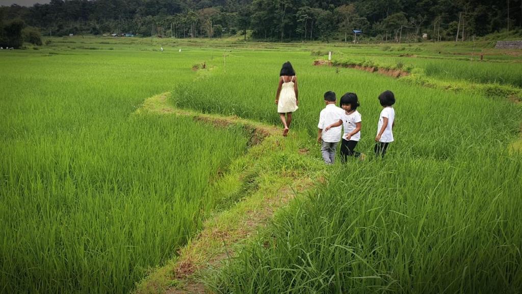a woman and three children walking in a field at Wayanad Kuruva Isles Jungle Resort in Chekadi