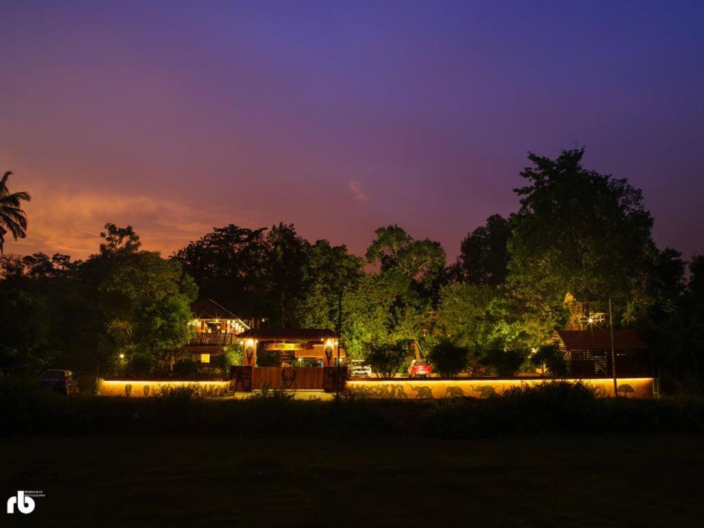 a house with lights on in a field at night at Wayanad Kuruva Isles Jungle Resort in Chekadi