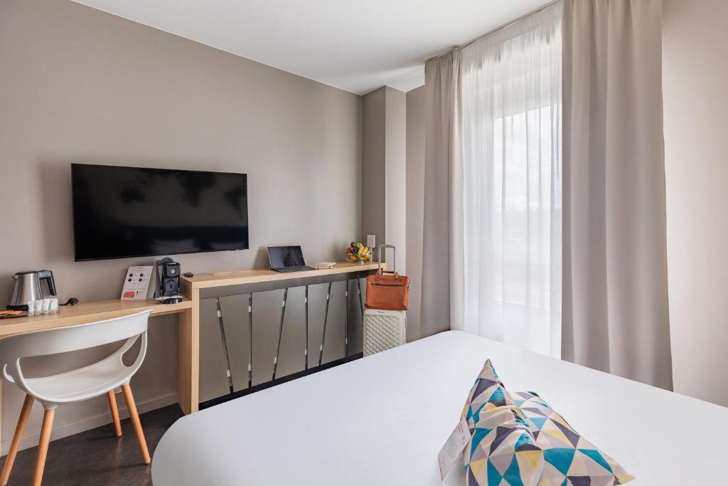 a bedroom with a bed and a desk and a television at Appart’City Confort Le Bourget - Aéroport in Le Bourget