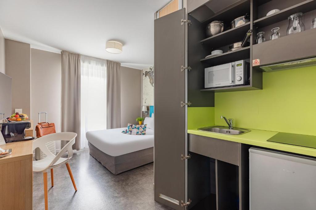 a kitchen and a bedroom with a bed in a room at Appart’City Confort Le Bourget - Aéroport in Le Bourget