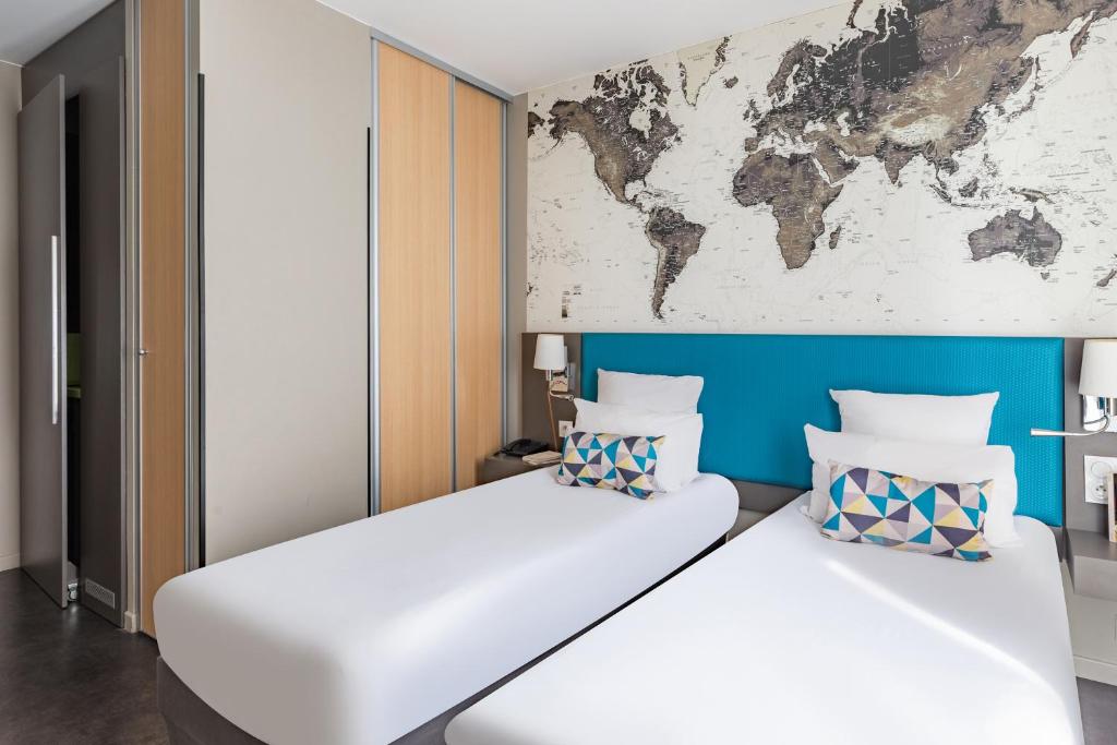 a bedroom with two beds with a map on the wall at Appart’City Confort Le Bourget - Aéroport in Le Bourget